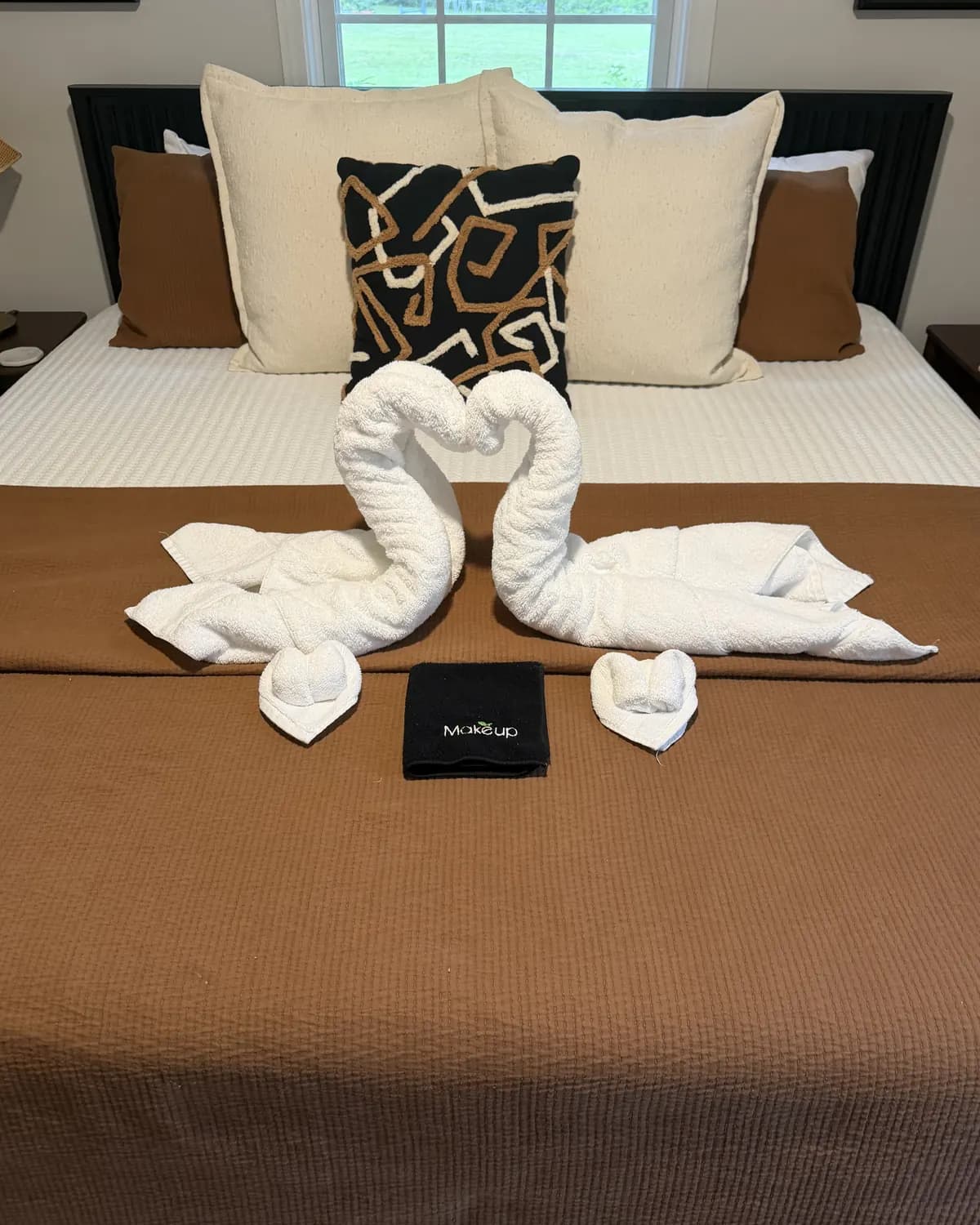 Towels folded into a pair of swans on a freshly made bed at the end of a KPD clean